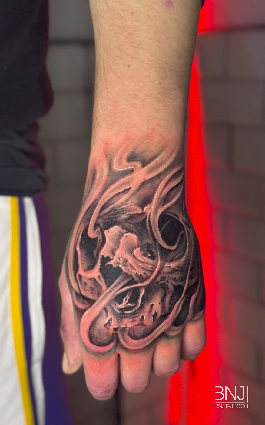 Tatuaje en la mano, calavera y flores en blanco y negro